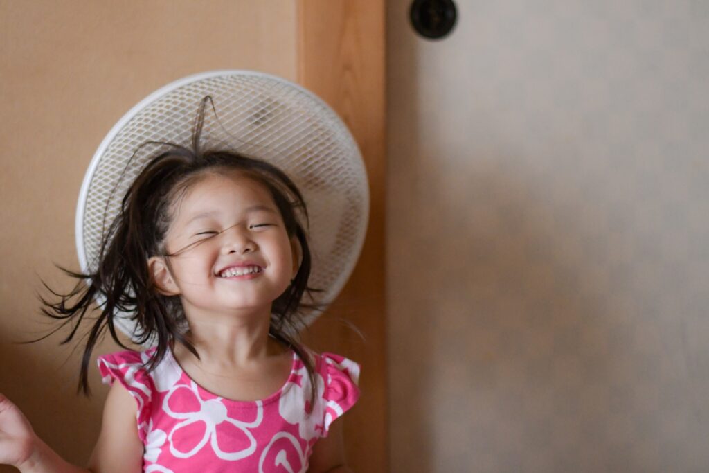 掃除前後の扇風機の違い、清潔な風を感じて笑顔になる子どもの様子。