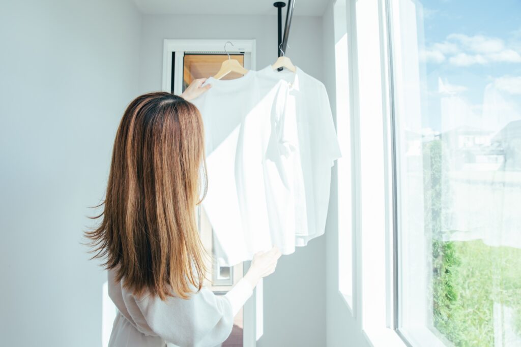 干し終えたハンガー付きの衣類をクローゼットにそのまま収納する様子