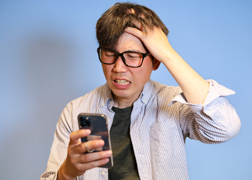 スマホの認証コード画面を見る男性